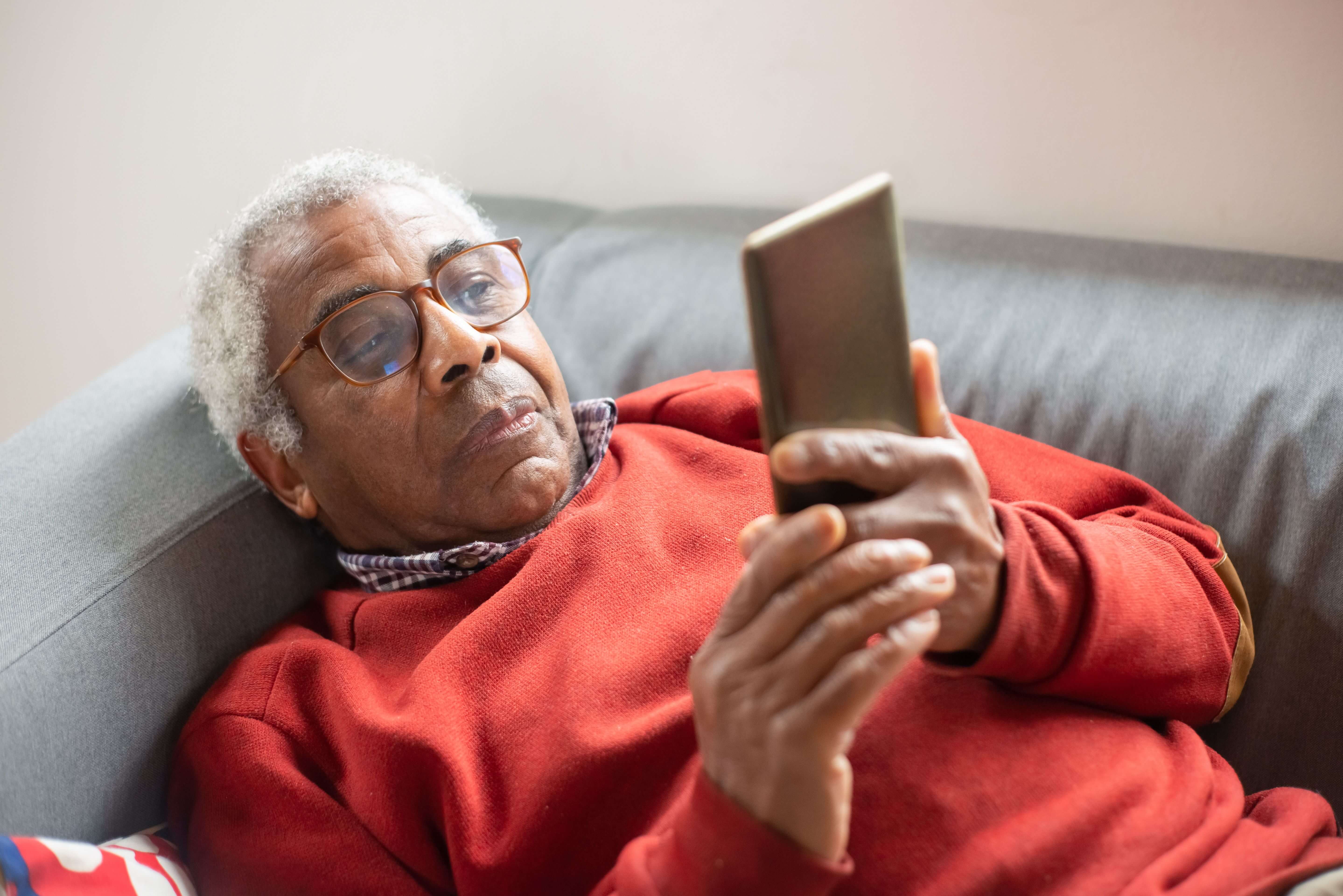 Älterer Mann am Smartphone, entspannt nach gelöstem Problem